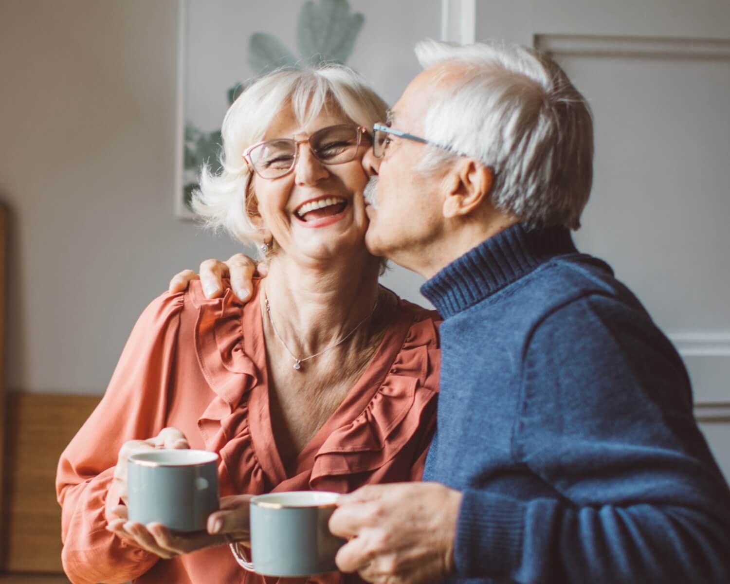 Senior standing in the kitchen and drinking tea or coffee.